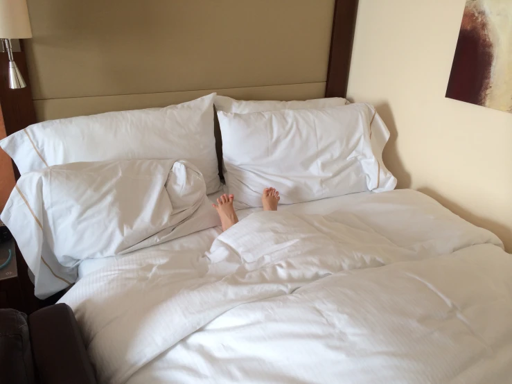 a person's feet in an unmade bed