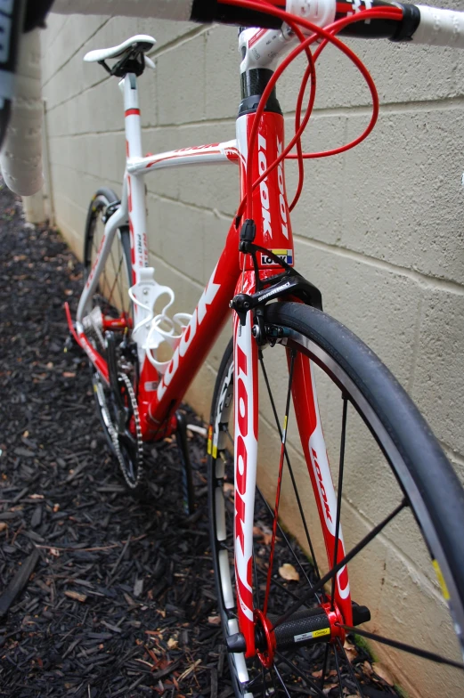 red and white bike leaning up against a brick wall