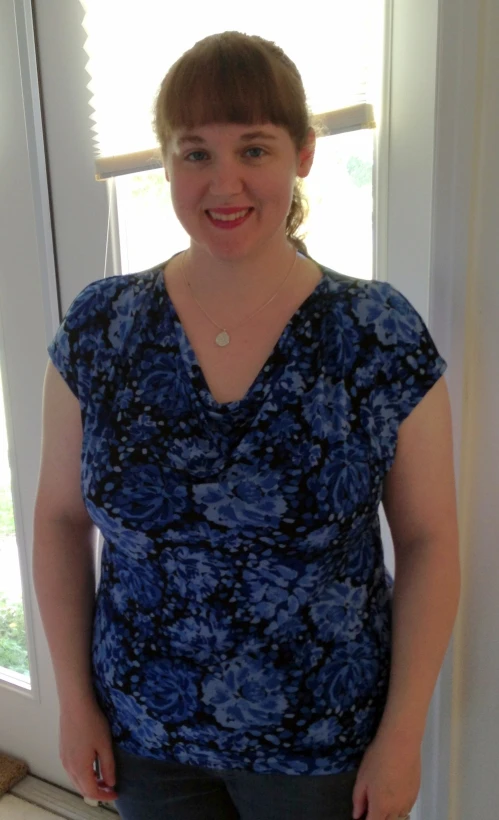 a woman wearing a blue dress smiling next to a window