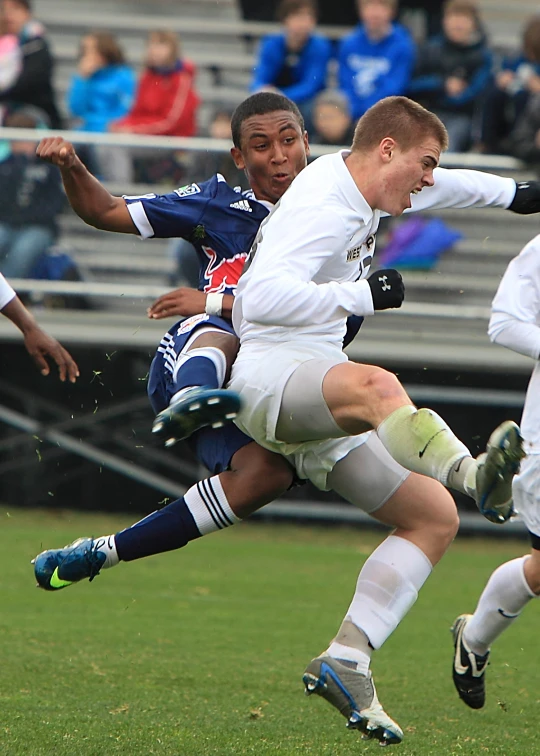 a pair of young men kicking a soccer ball on a field