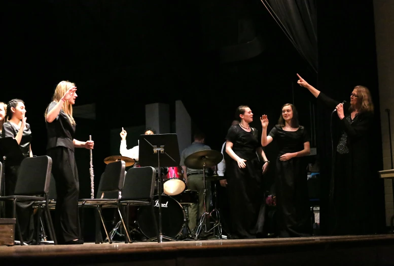 a group of people on stage singing into microphones