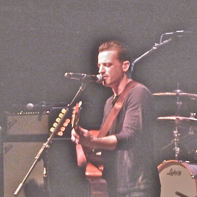 a man playing an orange guitar next to a microphone and guitar
