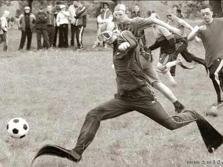 a man kicking a soccer ball in front of a group of people