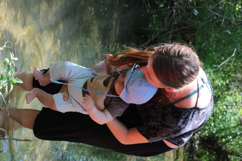 a woman holding her baby on his arm and he has sunglasses on his head