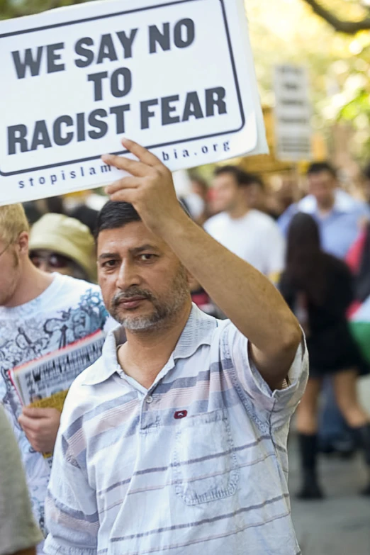 a protestor holding up a sign in front of a crowd