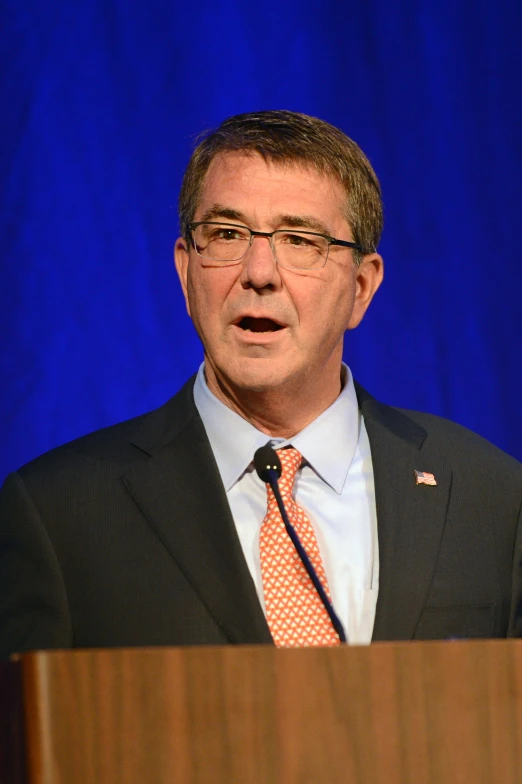 man wearing glasses and an orange neck tie, making a face