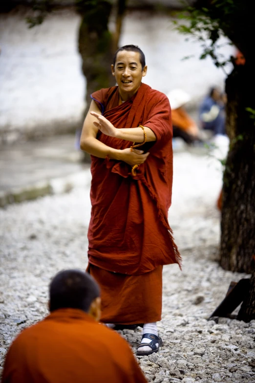 monk in red robe holding onto soing with other people sitting around