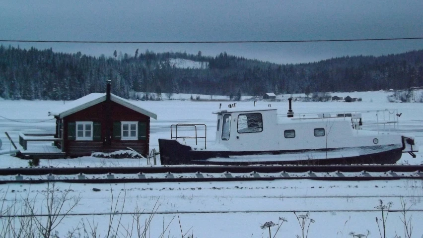 a tug boat sits on the snow covered land