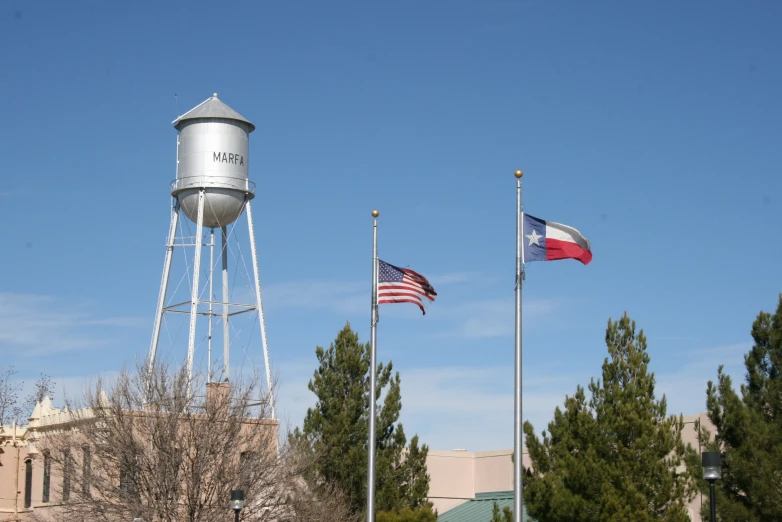 three flag flags are waving next to a water tower