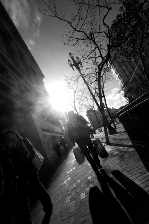 black and white po of people walking in the sun on the sidewalk