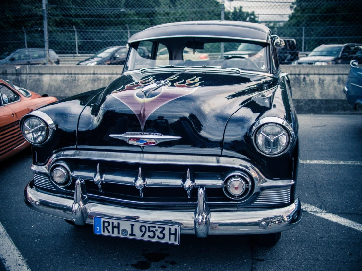 a classic car parked in a lot with other old cars