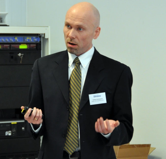 the man is talking while he stands in front of some computers