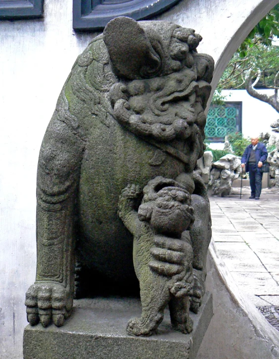 a cement dog statue holding a dog on it's paws