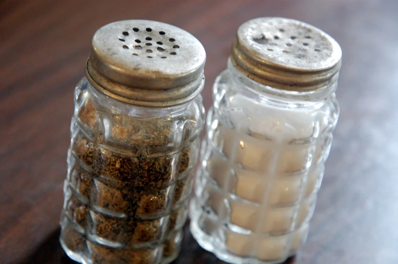 two salt and pepper shakers sitting on top of a wooden table