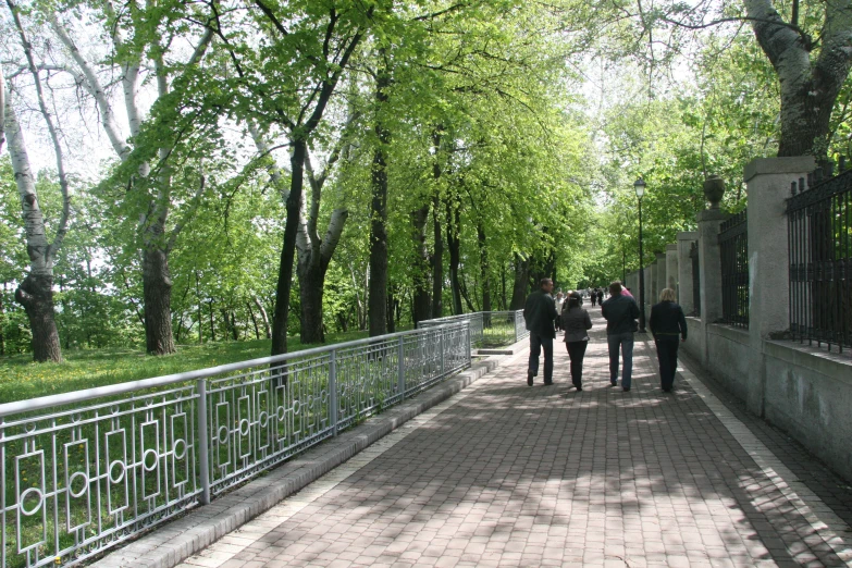 people walking down a brick road under trees