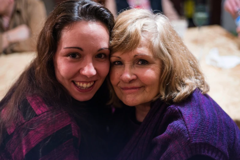 two women in purple sweaters hugging each other