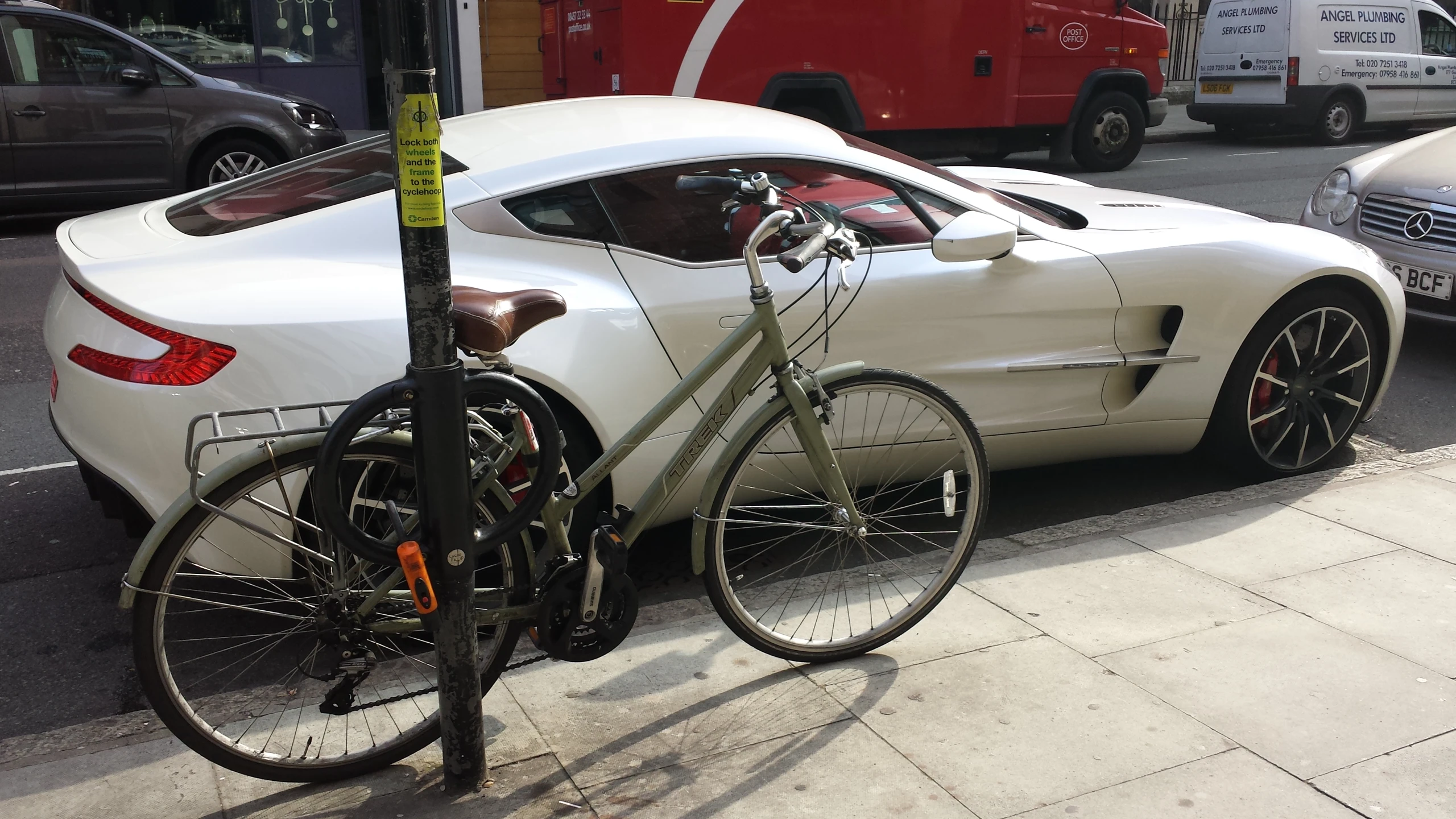 a bike sits next to a sports car