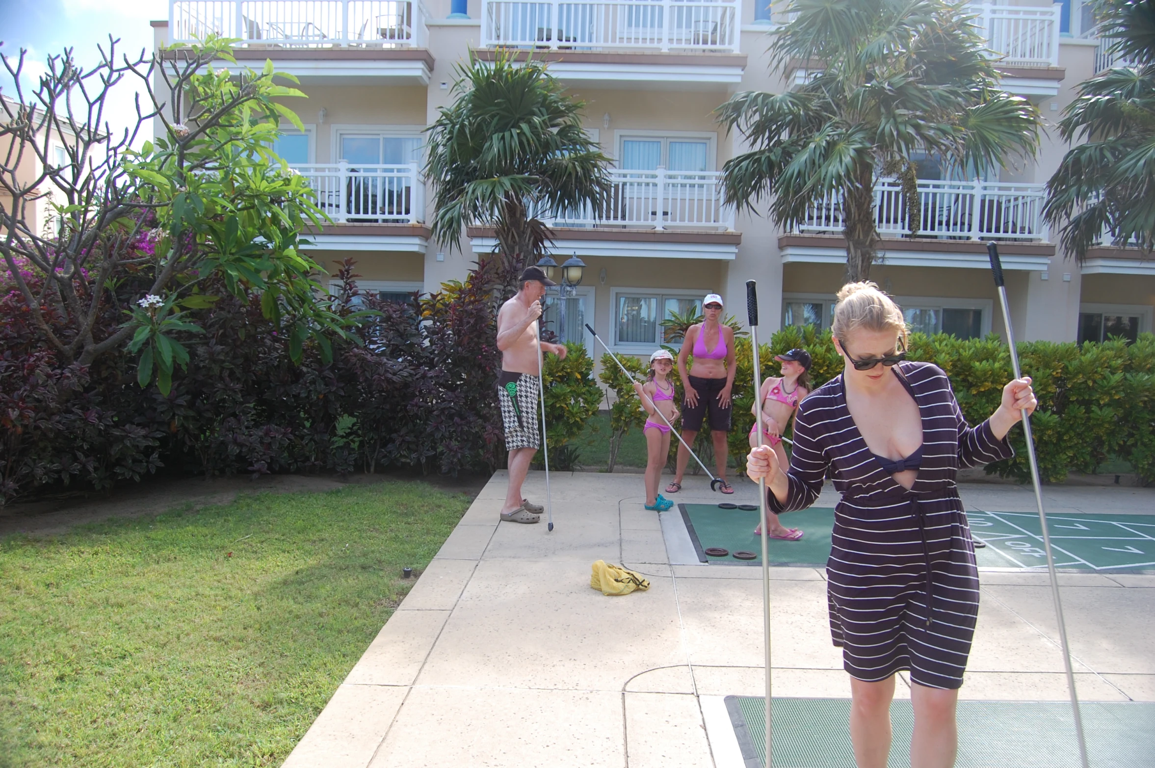 people playing miniature golf on the walkway near an apartment complex