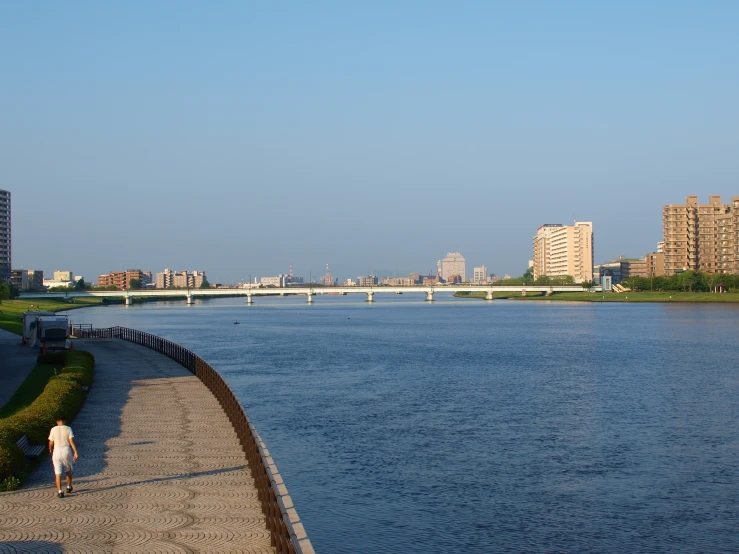 two people walk on the side of a city river