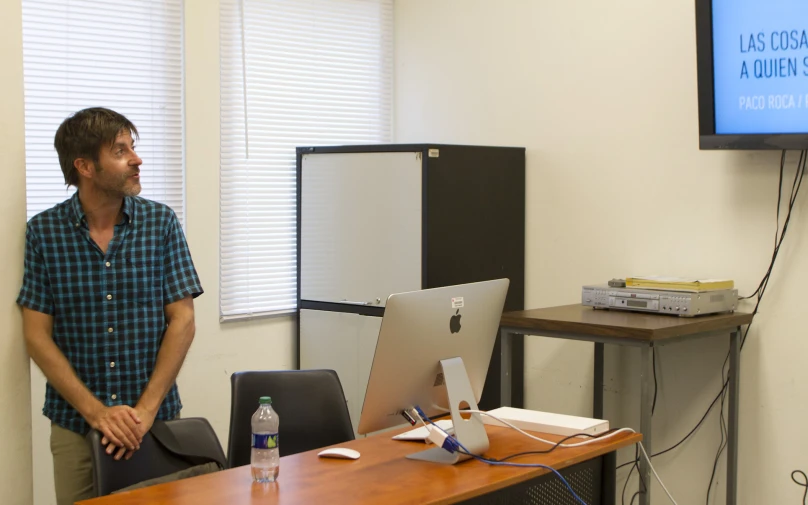 a man is standing in front of a computer screen