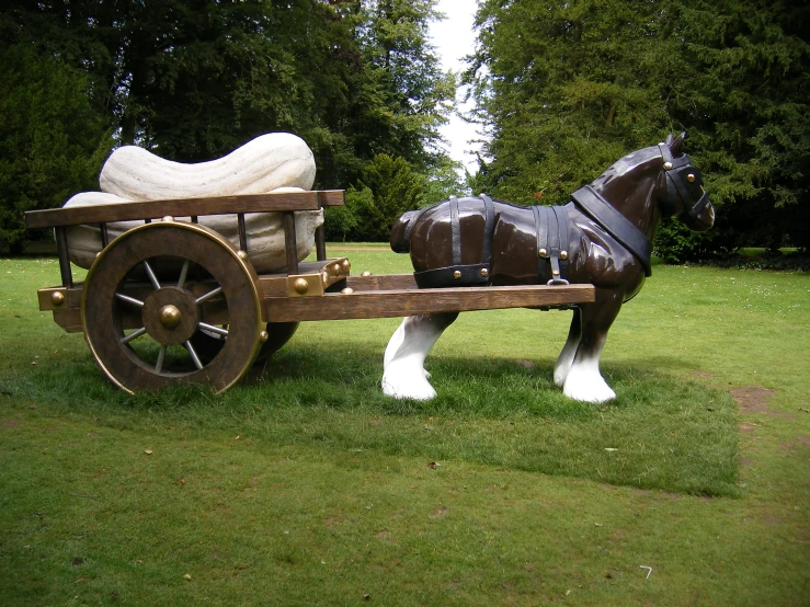 a toy horse pulling a carriage in the grass