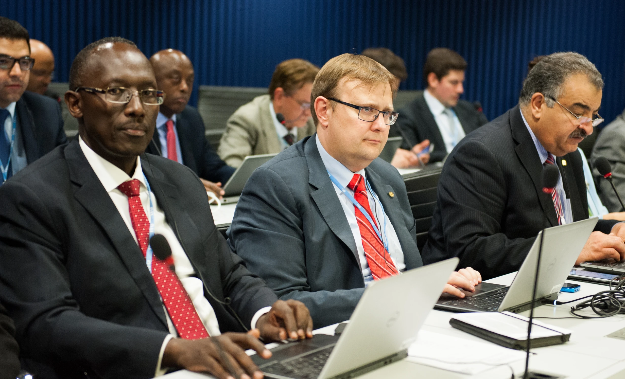 four men sitting at tables in suits and ties