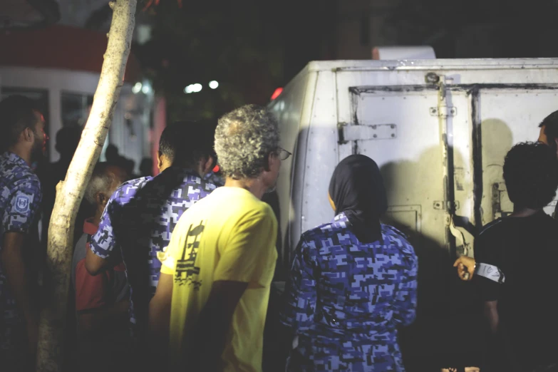 several people are standing by a very large truck