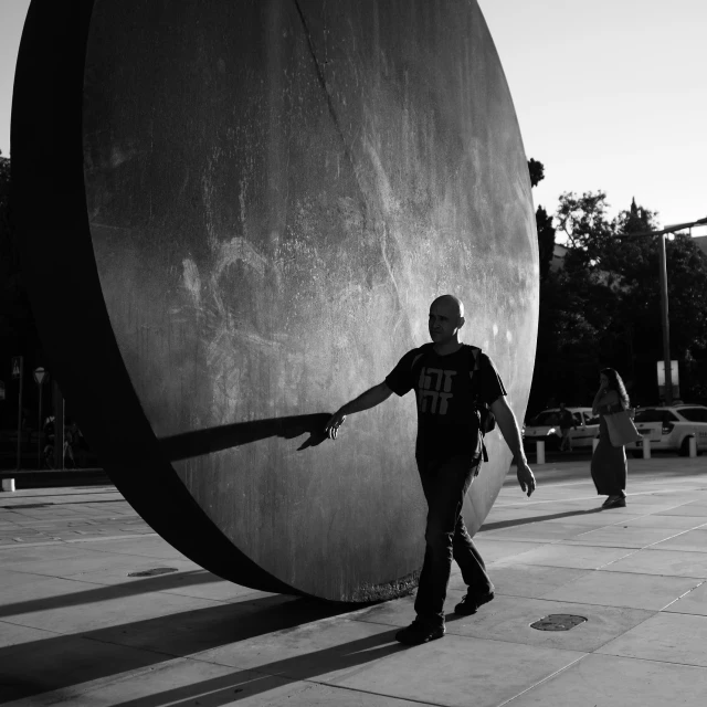 man walking in front of an art sculpture in black and white