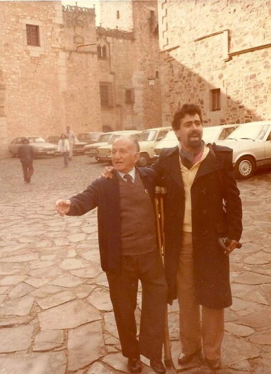 two men standing in front of old stone buildings