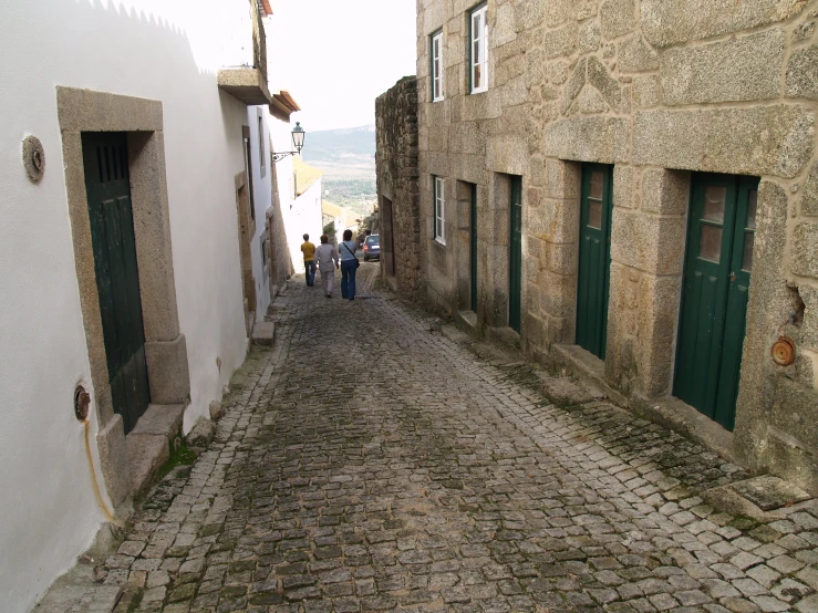 a couple people are on a narrow cobblestone street