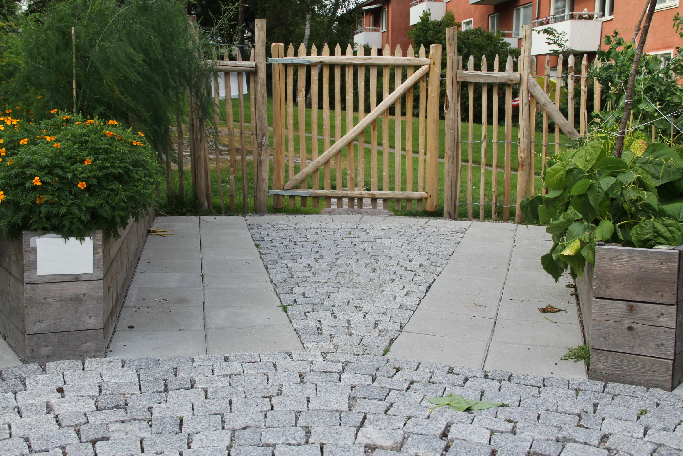 a garden with stone paths, a wooden gate and various flowers