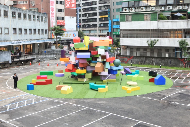 a colorfully designed circular playground set sits in the middle of an empty parking lot