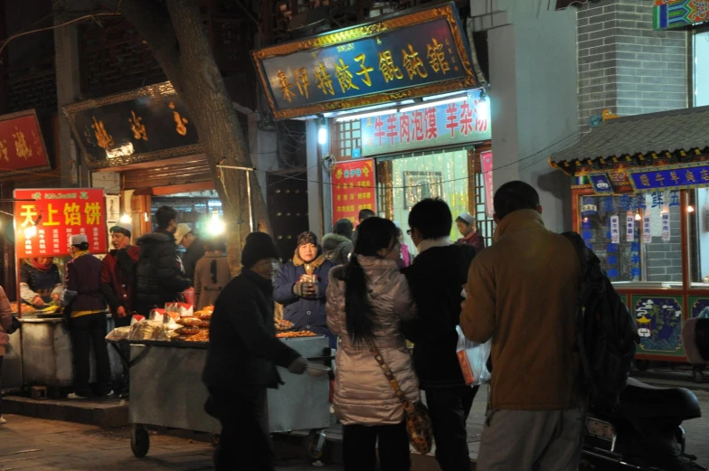 a group of people outside a store in a town at night