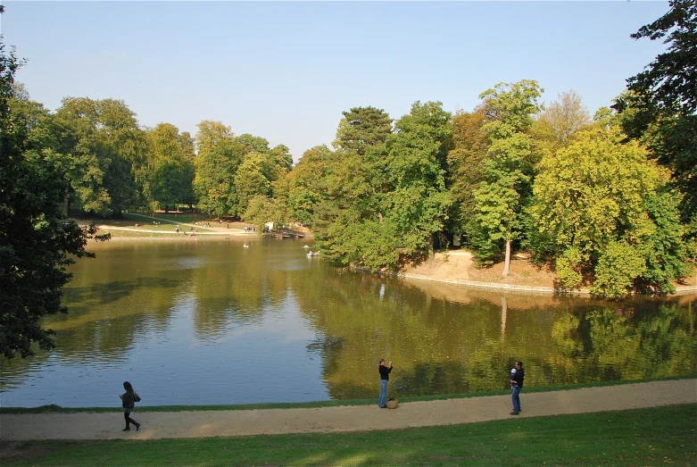 a couple of people walking near water and trees