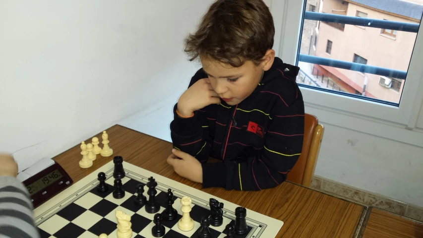 a child sitting at a table playing chess