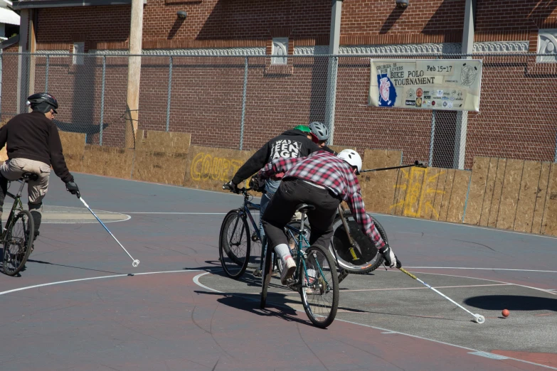 two people on bicycles in front of a fenced area