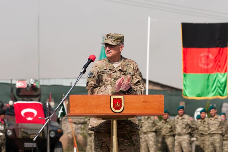 a man in army fatigues speaks at a podium