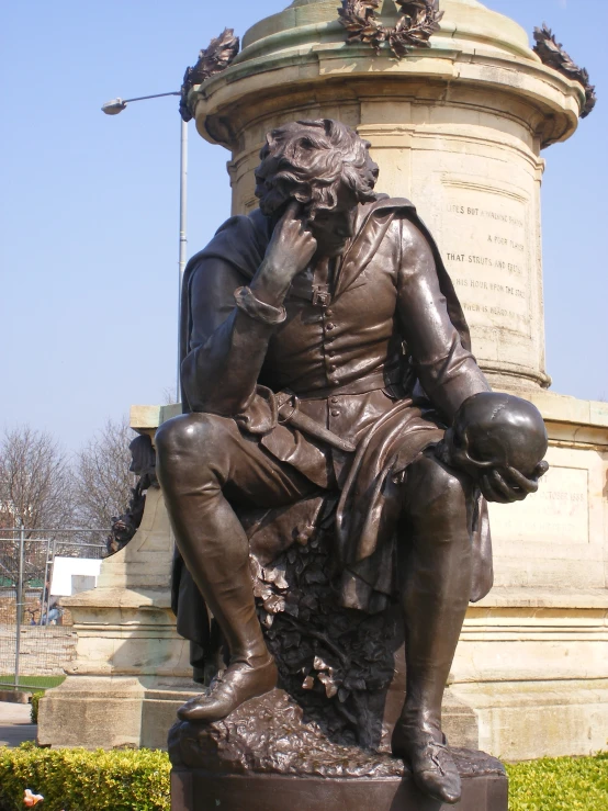a statue of a seated man with a book and a cigarette