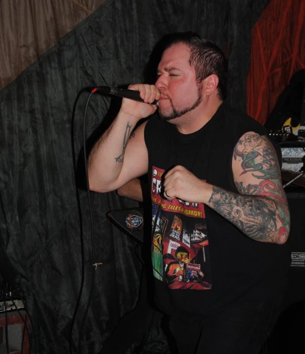 a man with a black shirt on holds a mic in front of him