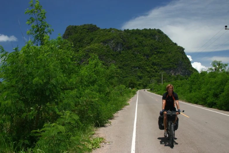 the person is riding their bicycle down the road