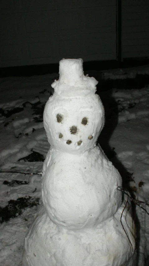 a snowman sitting outside on a snowy surface