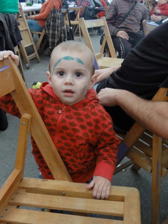 a child with face paint sitting in a chair