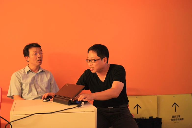 a man sitting at a desk with another man