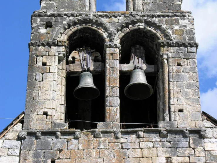 two bells sitting on the side of a stone building