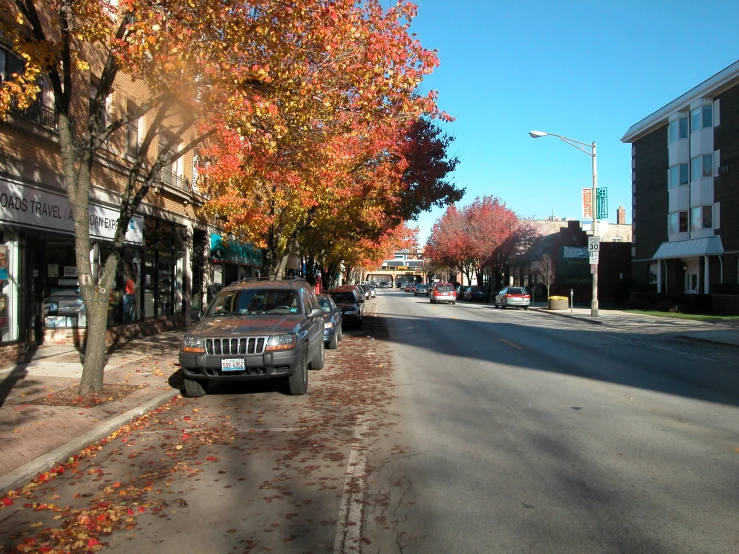 several cars on a quiet city street lined with shops