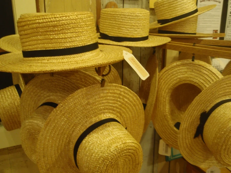straw hats are hanging up in a display at the store