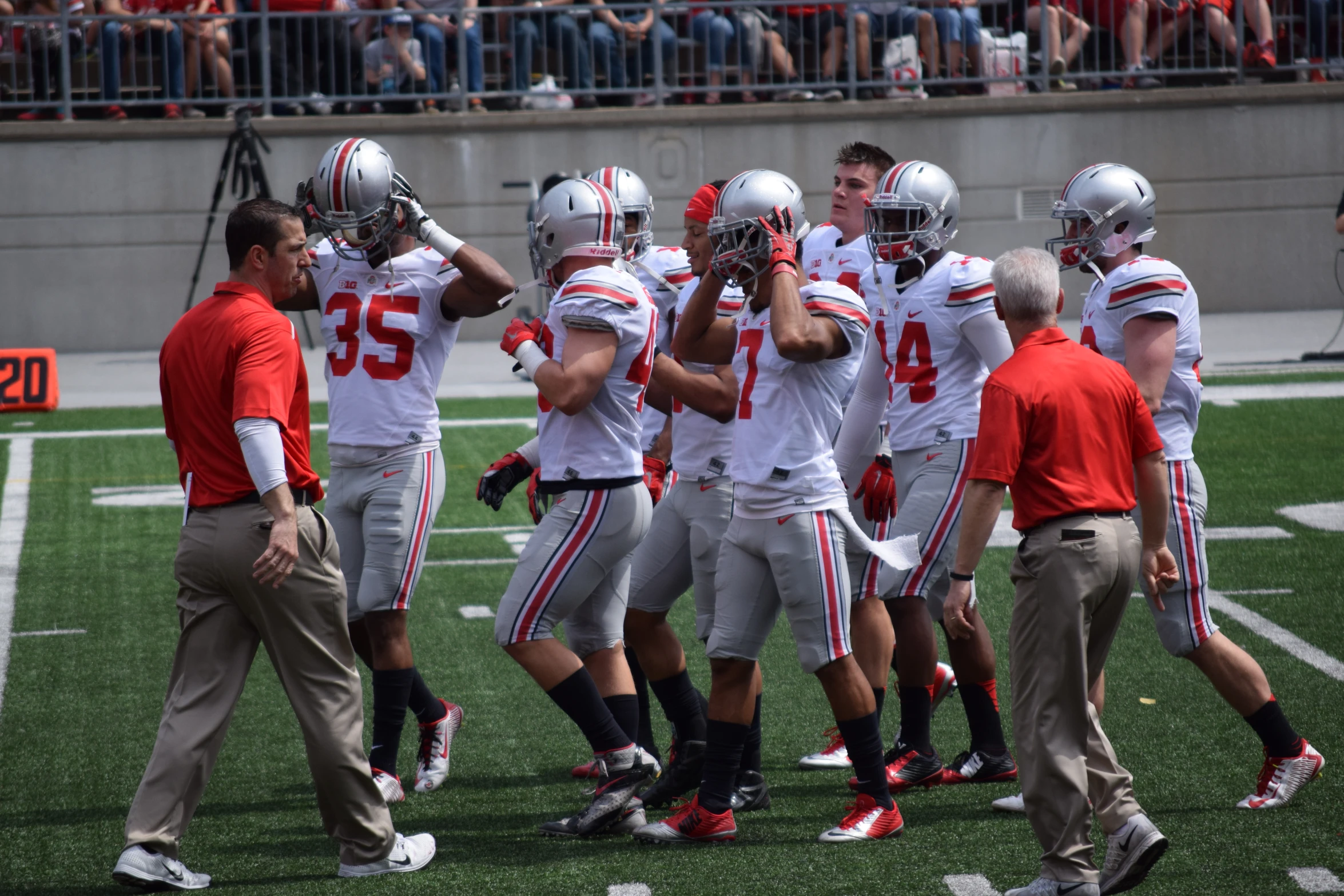 a group of football players standing on a field with a coach