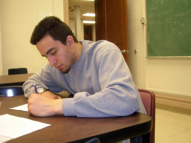 a young man taking notes at a desk