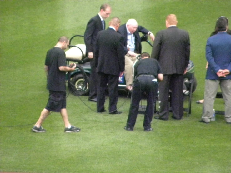 a group of people in suits walking on a grassy field