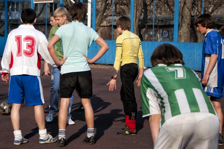 a group of boys playing soccer on an asphalt field